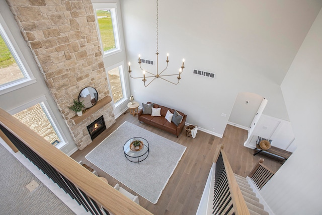 living room with a fireplace, a towering ceiling, hardwood / wood-style flooring, and a notable chandelier