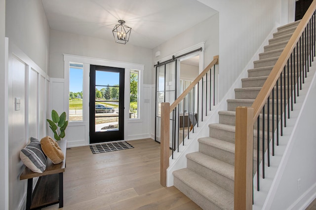 entrance foyer featuring a barn door, a notable chandelier, and light wood-type flooring