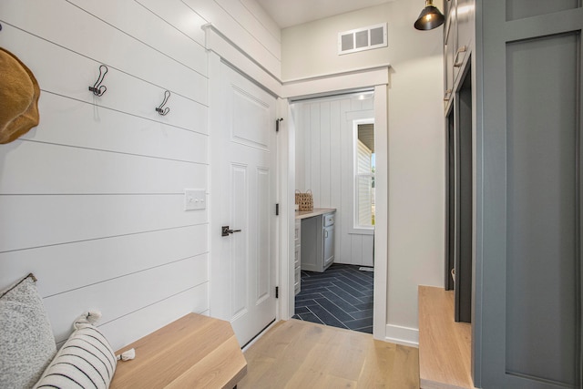 mudroom with light hardwood / wood-style flooring and wooden walls