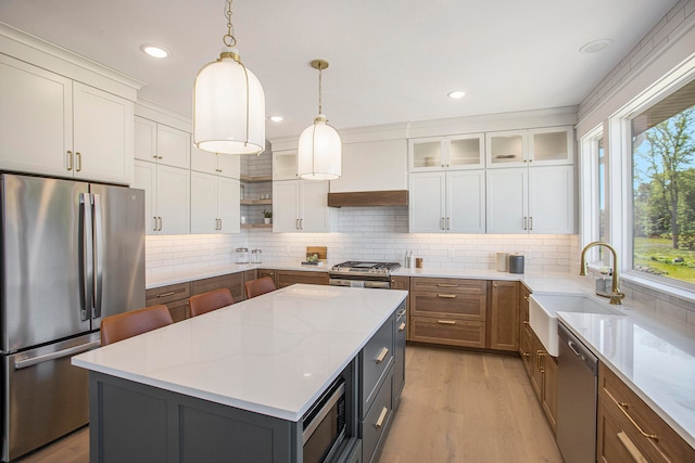 kitchen with white cabinets, a kitchen island, light stone countertops, and appliances with stainless steel finishes