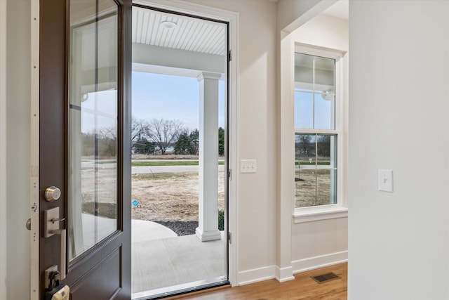 foyer entrance with plenty of natural light, visible vents, baseboards, and wood finished floors