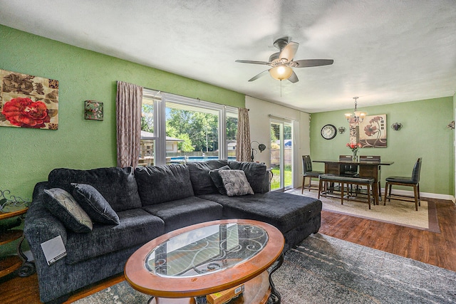 living room featuring ceiling fan with notable chandelier and dark wood-type flooring