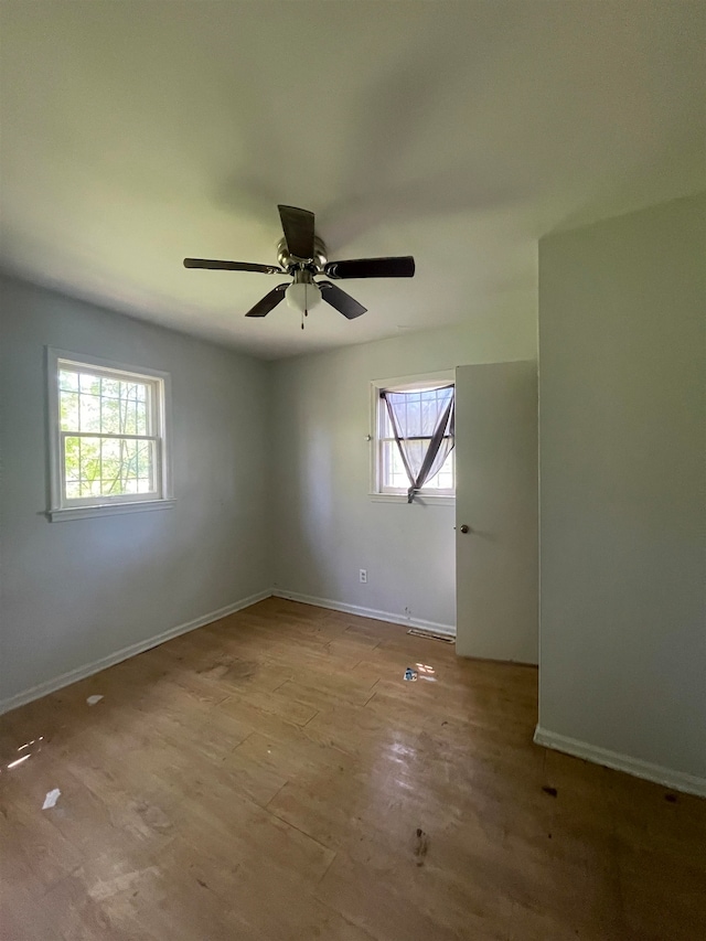 empty room featuring ceiling fan, a healthy amount of sunlight, and light hardwood / wood-style floors