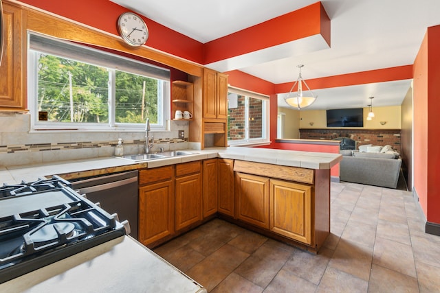 kitchen featuring kitchen peninsula, backsplash, sink, dishwasher, and hanging light fixtures