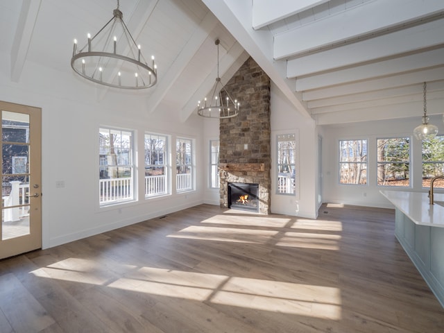 unfurnished living room with beam ceiling, a stone fireplace, wood-type flooring, and high vaulted ceiling