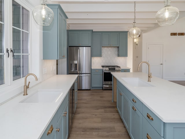 kitchen with an island with sink, sink, appliances with stainless steel finishes, and dark wood-type flooring