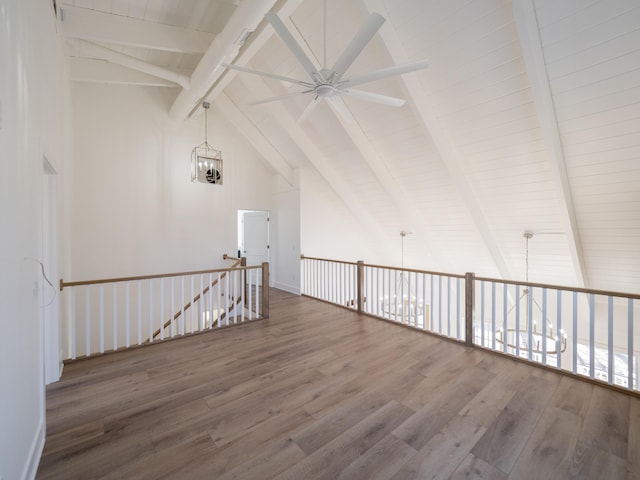 spare room featuring beamed ceiling, wood-type flooring, ceiling fan with notable chandelier, and high vaulted ceiling