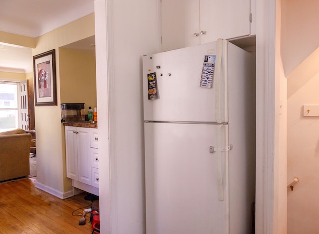 kitchen with white fridge, light wood-type flooring, and white cabinetry