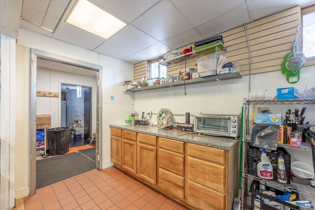 18564 200th, Tustin, MI 49688 - kitchen featuring light tile patterned floors, open shelves, brown cabinets, a drop ceiling, and stone counters