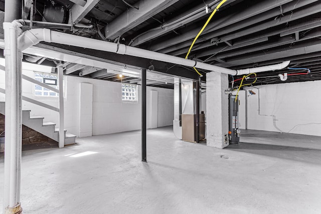 basement featuring heating unit, a wealth of natural light, and water heater