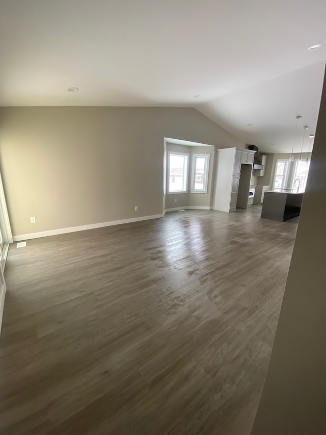 unfurnished living room with lofted ceiling and dark wood-type flooring