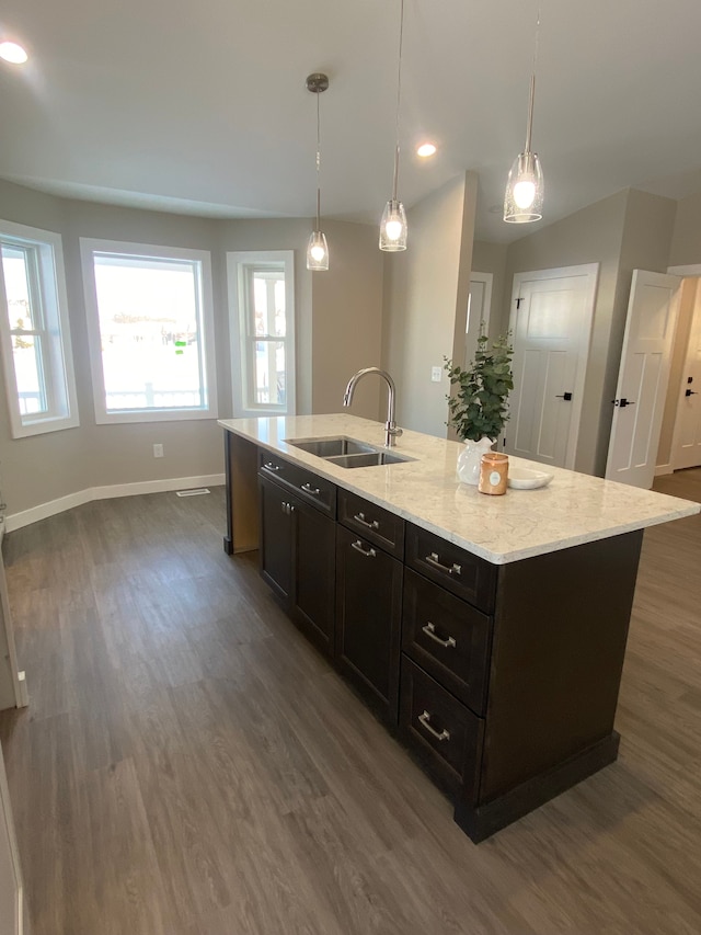 kitchen with sink, decorative light fixtures, and an island with sink