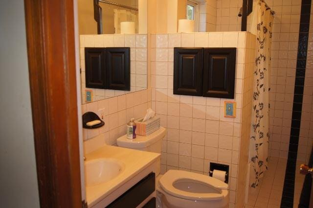 bathroom featuring toilet, walk in shower, and tile walls