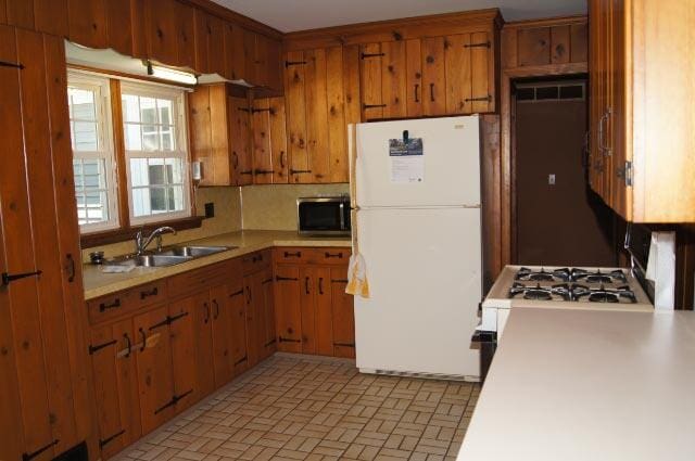 kitchen with decorative backsplash, white appliances, and sink