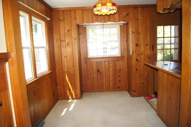 dining room featuring wooden walls and light carpet