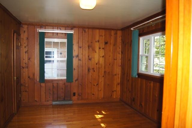 unfurnished room with wood-type flooring and wood walls