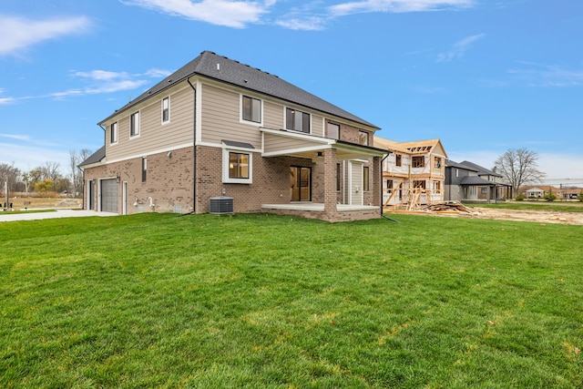 rear view of house featuring a yard, a garage, and central AC unit