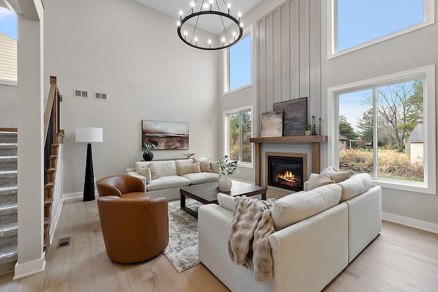 living room featuring light hardwood / wood-style flooring, a towering ceiling, and a chandelier