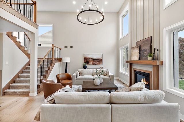 living room featuring a high ceiling, light wood-type flooring, and an inviting chandelier