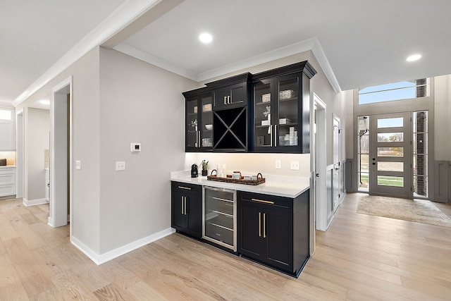 bar featuring ornamental molding, beverage cooler, and light hardwood / wood-style flooring