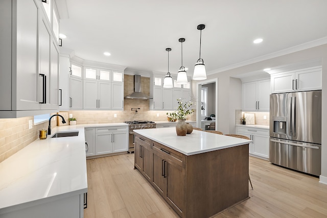 kitchen with stainless steel appliances, wall chimney range hood, light hardwood / wood-style flooring, a center island, and white cabinetry