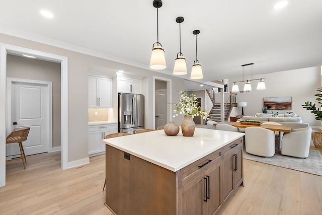 kitchen with stainless steel fridge, white cabinetry, light hardwood / wood-style flooring, and a kitchen island