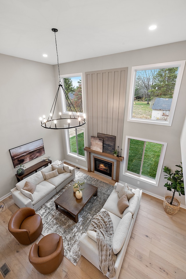 living room featuring light wood-type flooring, a wealth of natural light, and a notable chandelier