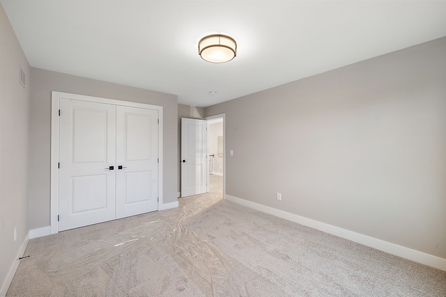 unfurnished bedroom with light carpet and a closet