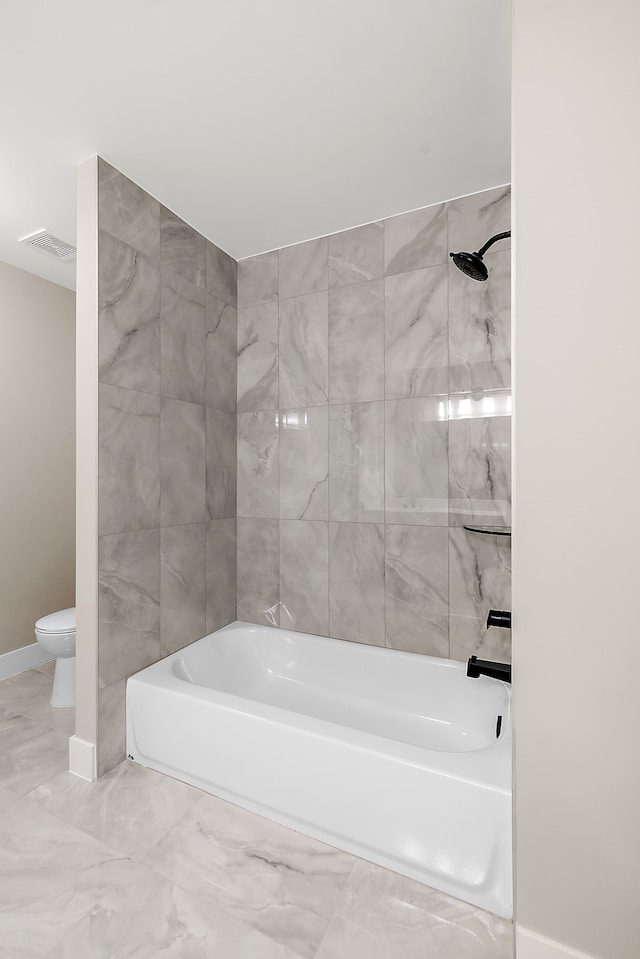 bathroom featuring tiled shower / bath combo and toilet