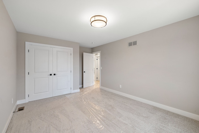 unfurnished bedroom with light carpet and a closet