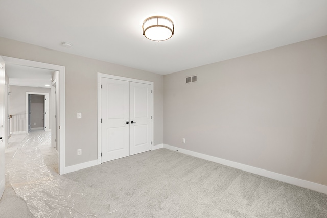 unfurnished bedroom with light carpet and a closet