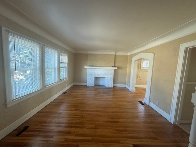 unfurnished living room featuring crown molding, dark wood-type flooring, and a brick fireplace