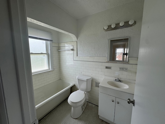 bathroom featuring a tub, tile patterned floors, toilet, vanity, and tile walls