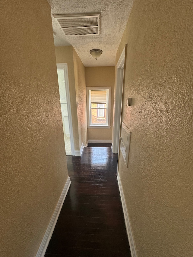 hall with a textured ceiling and dark hardwood / wood-style floors