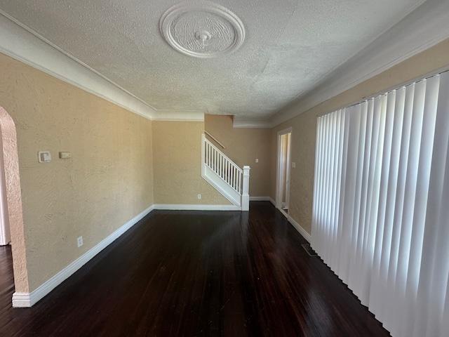 unfurnished living room with dark hardwood / wood-style flooring, a textured ceiling, and ornamental molding