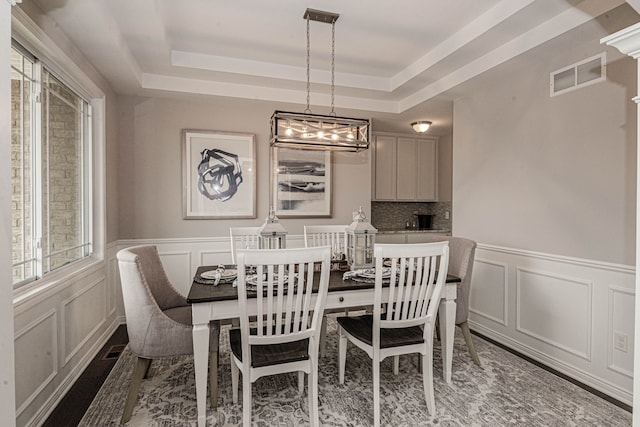 dining area with dark hardwood / wood-style flooring and a raised ceiling