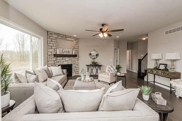 living room featuring ceiling fan, a fireplace, and dark hardwood / wood-style floors