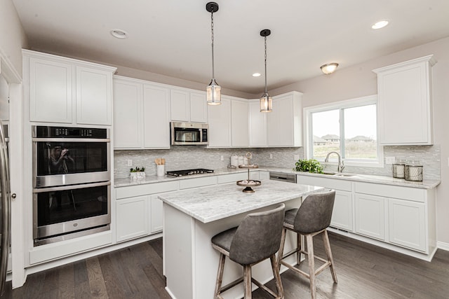 kitchen featuring backsplash, stainless steel appliances, a kitchen island, dark wood-type flooring, and white cabinetry