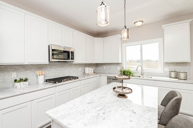 kitchen with white cabinetry, hanging light fixtures, stainless steel appliances, tasteful backsplash, and a breakfast bar