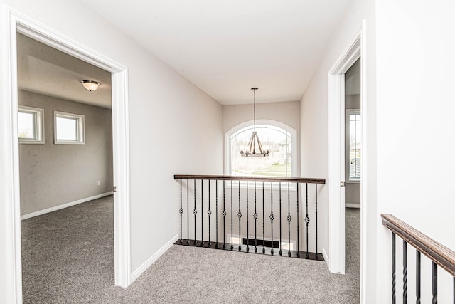 hallway with carpet flooring and a notable chandelier