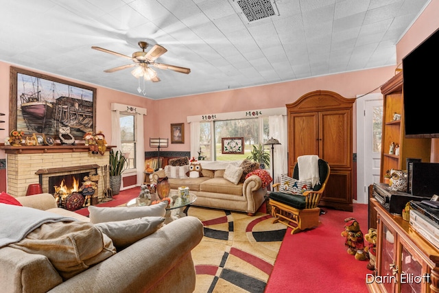 carpeted living area featuring a brick fireplace, visible vents, and a ceiling fan