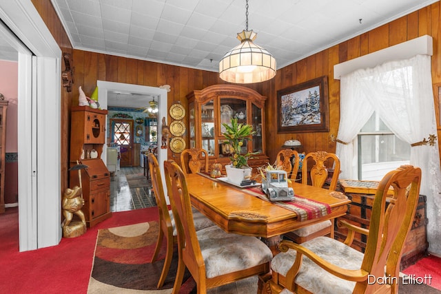 dining space featuring carpet floors and wood walls