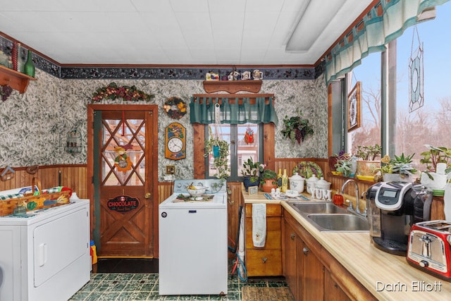 kitchen featuring wallpapered walls, wainscoting, light countertops, and washer / dryer