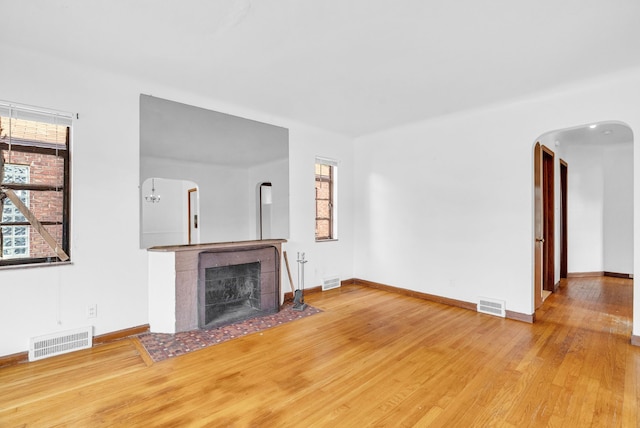 unfurnished living room with plenty of natural light, wood-type flooring, and a tiled fireplace