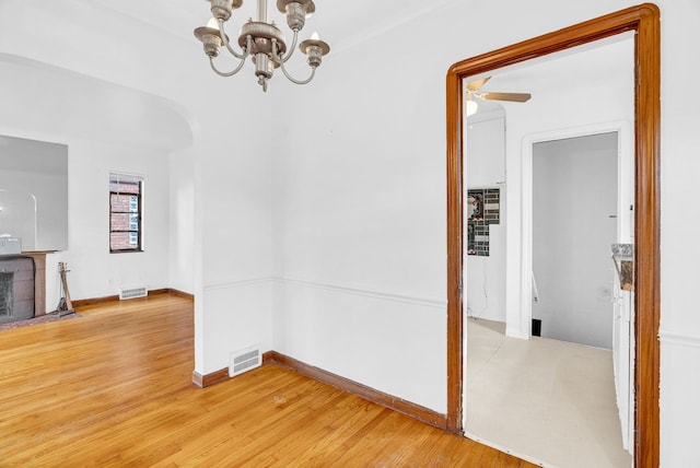 interior space with ceiling fan with notable chandelier and light wood-type flooring