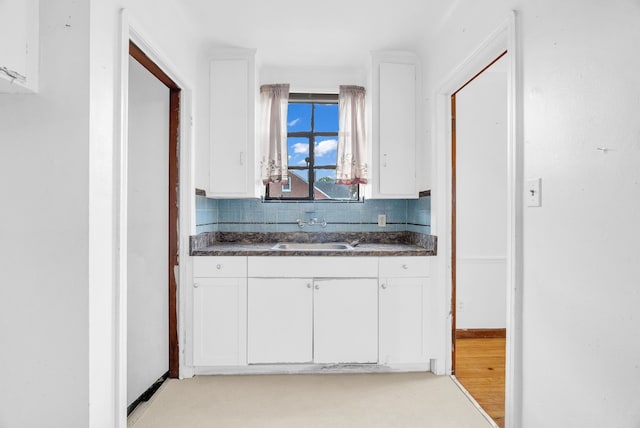 kitchen with backsplash, light hardwood / wood-style floors, white cabinetry, and sink