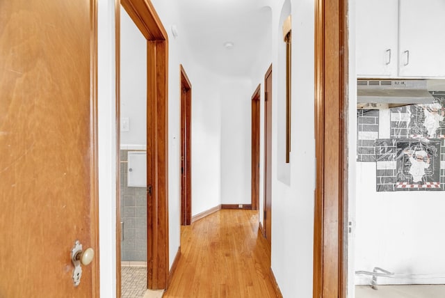 corridor with light wood-type flooring and tile walls