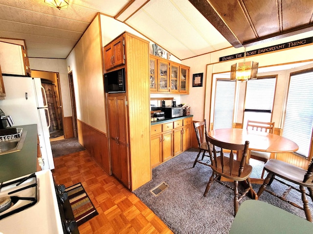 831 S Main St, Au Gres, MI 48703 - kitchen with lofted ceiling, brown cabinets, glass insert cabinets, gas range, and wainscoting