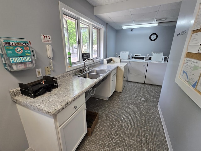 831 S Main St, Au Gres, MI 48703 - kitchen with washing machine and clothes dryer, a sink, a paneled ceiling, light countertops, and white cabinetry