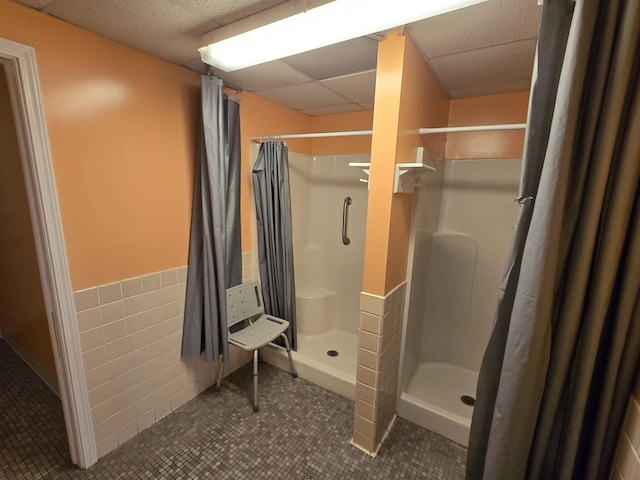 831 S Main St, Au Gres, MI 48703 - bathroom with a stall shower, a drop ceiling, tile patterned flooring, wainscoting, and tile walls